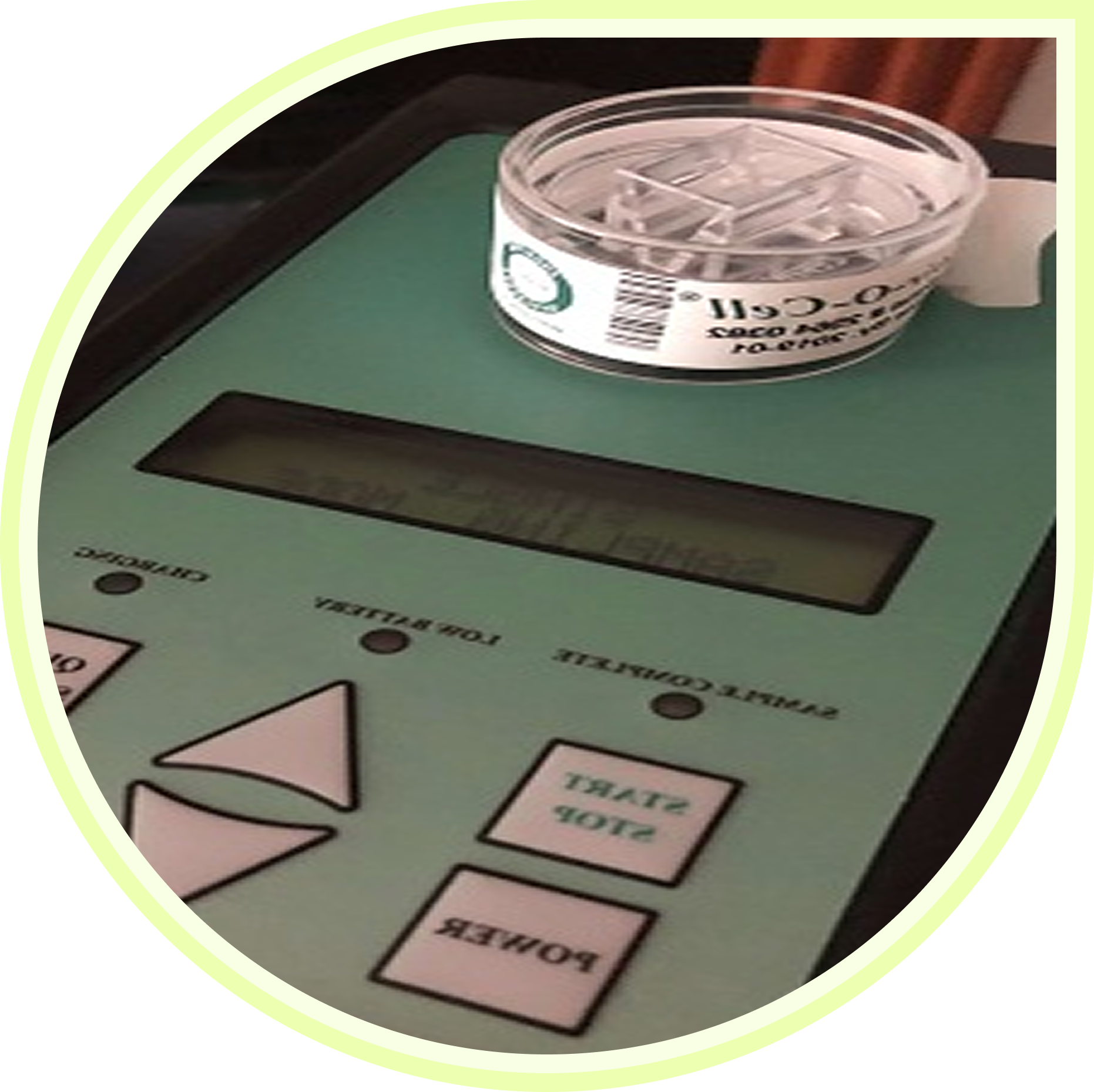 A close-up of a green electronic device with buttons and a small container on top.