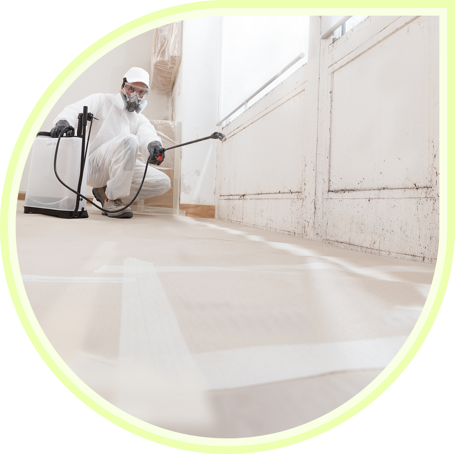 Person disinfecting floor and walls wearing protective gear.