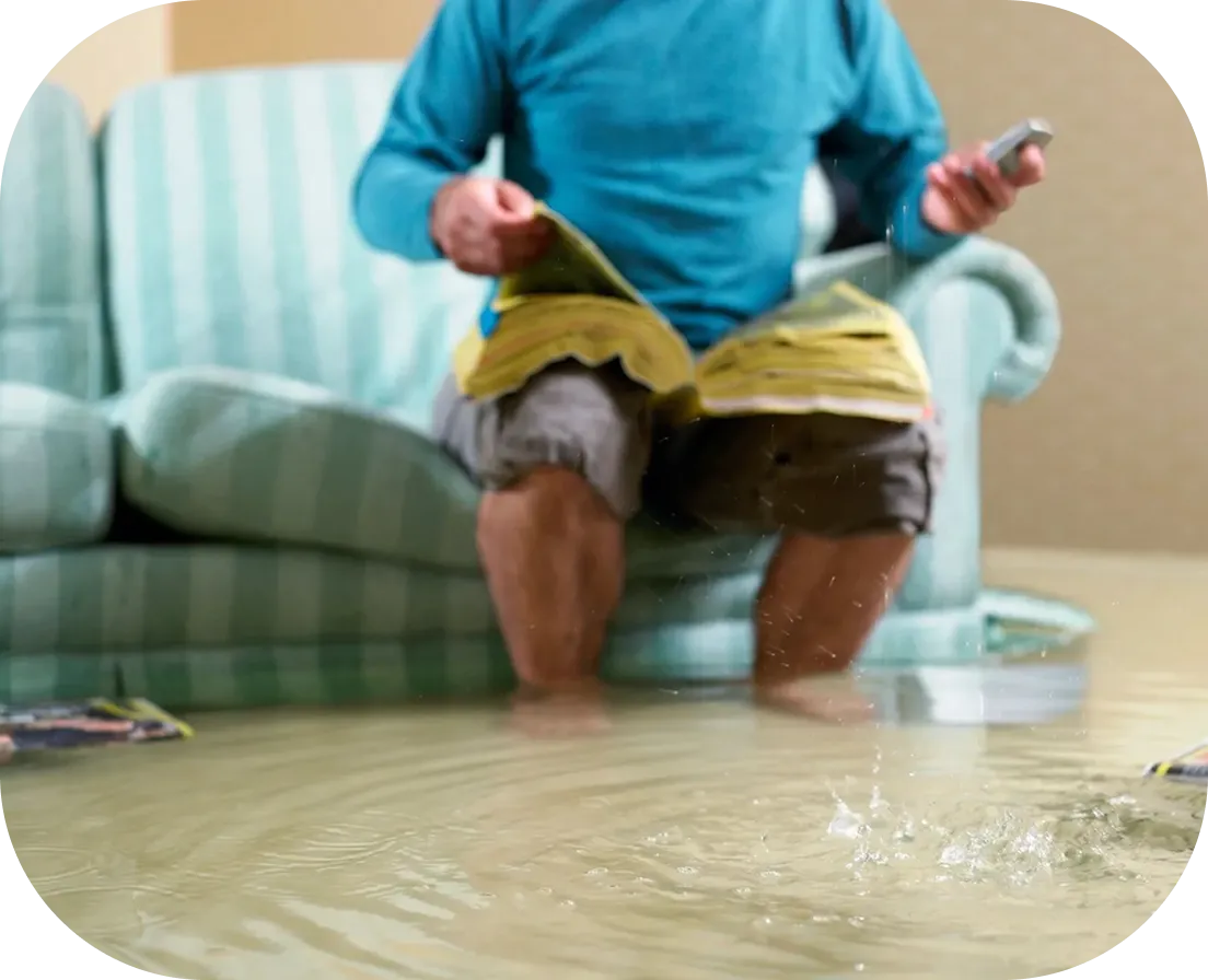 Man sitting on sofa in floodwater.